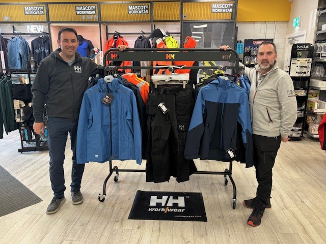 Two people outside a clothing rack in a workwear store.