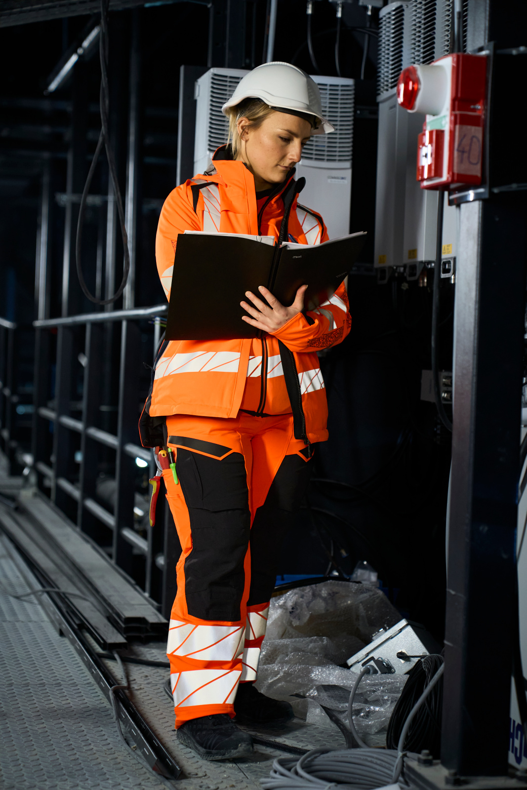 A woman wearing a hard hat, hi vis jacket and hi vis trousers.